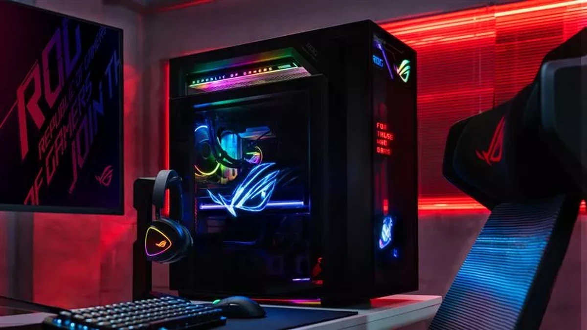 ASUS ROG gaming PC tower with RGB lighting on a desk beside a headset, keyboard and mouse under red light