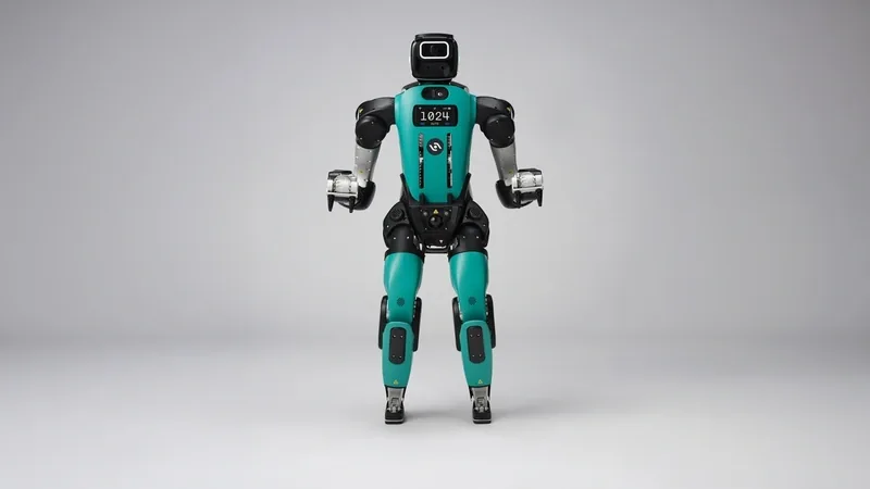 Agility Robotics Digit humanoid robot in teal and black standing against a gray studio backdrop