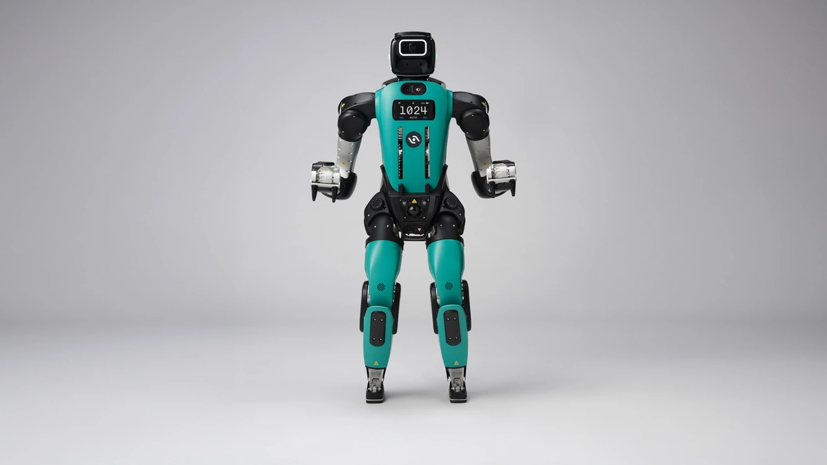 Agility Robotics Digit humanoid robot in teal and black standing against a gray studio backdrop