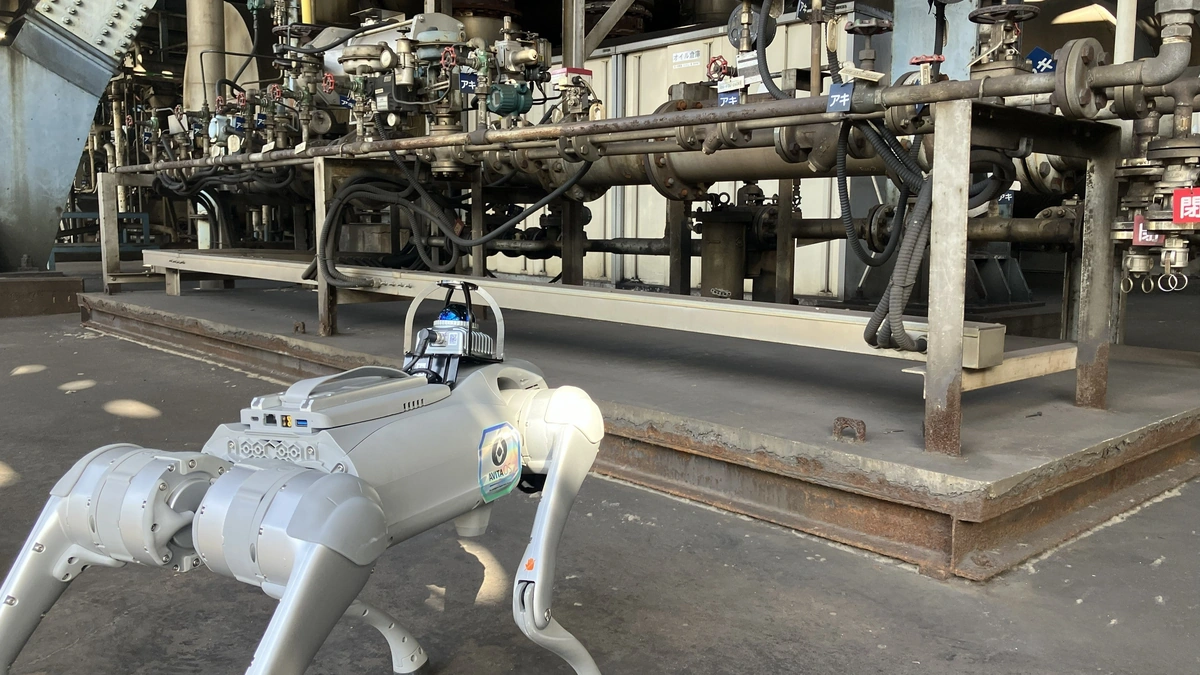 Quadruped robot with an AVITA OS badge standing before industrial piping at Daicel's plant