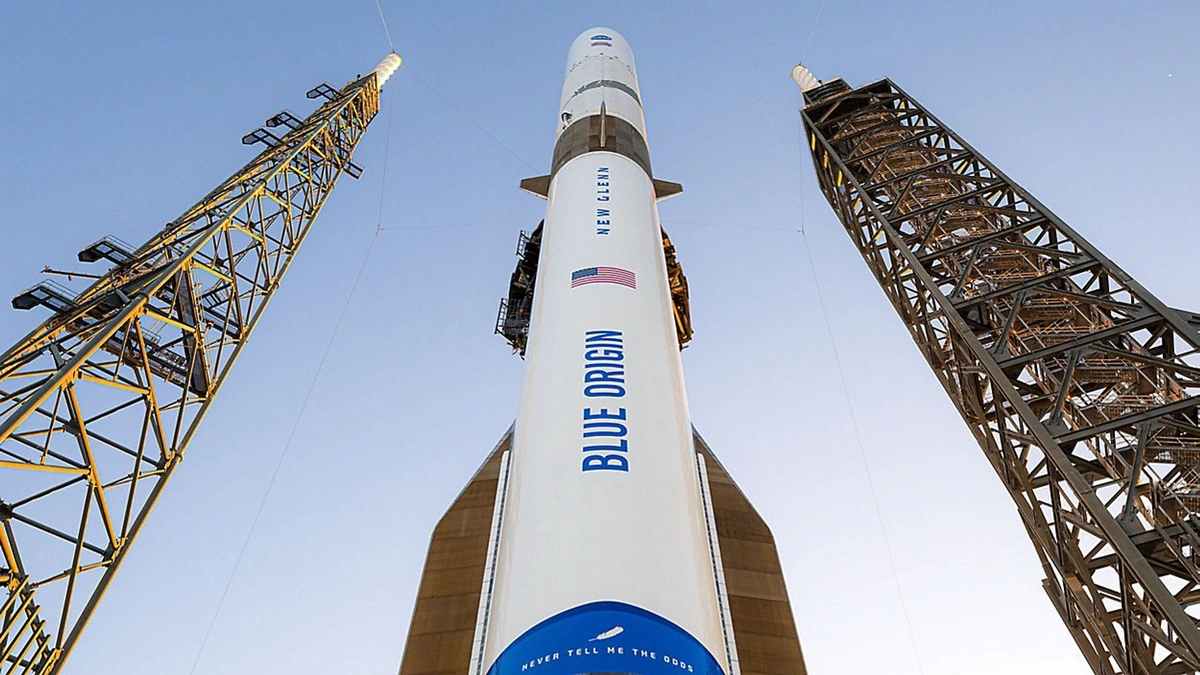 Blue Origin New Glenn rocket standing between launch towers, seen from below against a blue sky