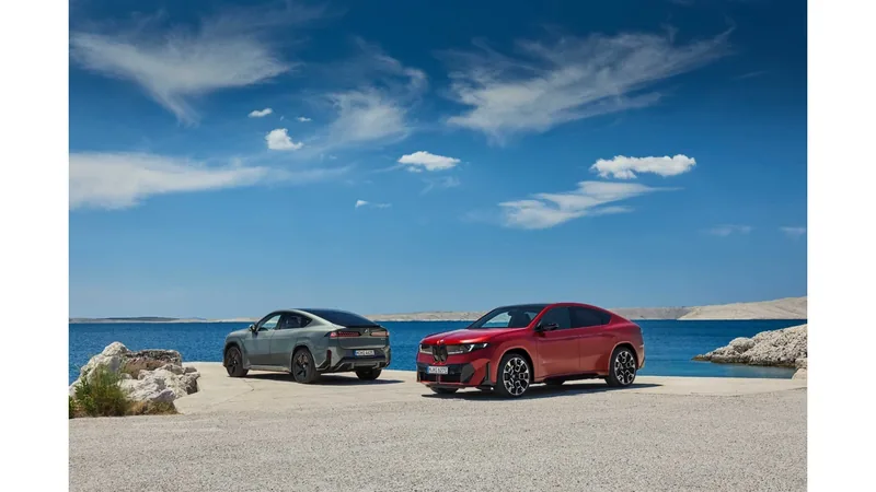 Red and gray BMW iX4 SUV coupes parked on a rocky seaside lot under a blue sky