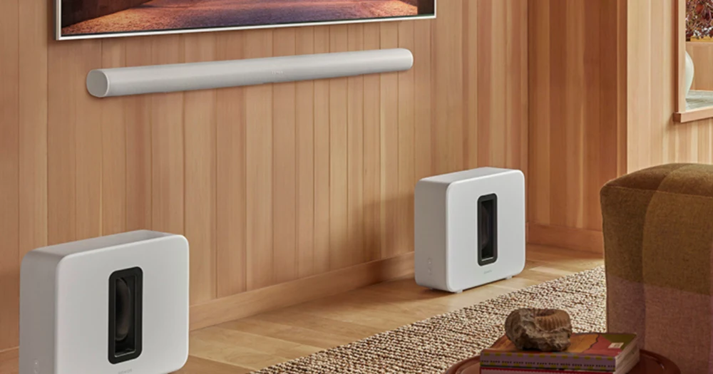 Sonos Arc Ultra soundbar shows a home theater audio setup on a wood-paneled wall above two white subwoofers