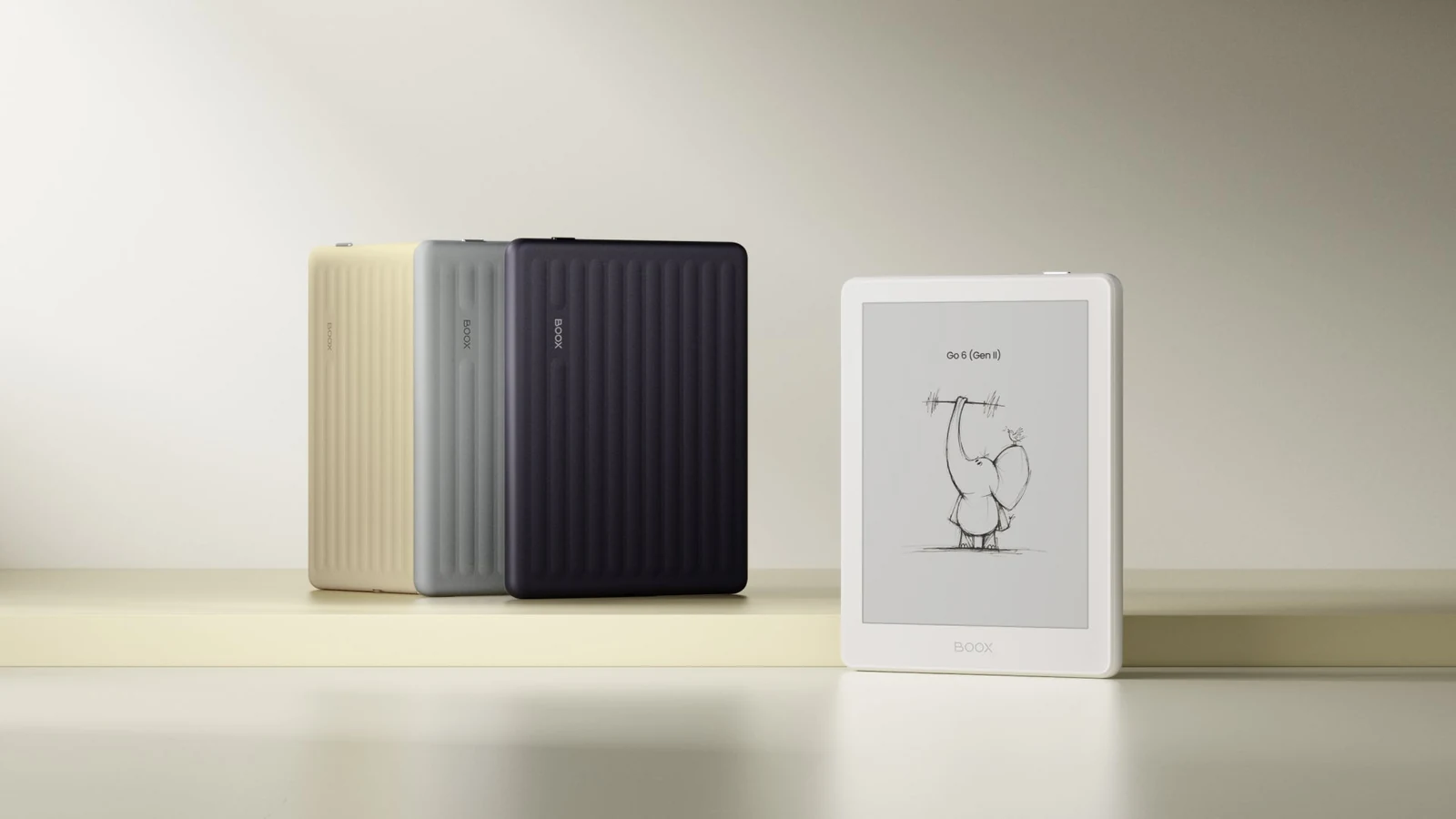 BOOX Go 6 e-reader shows a drawing on its screen in front of three colored device backs on a light shelf