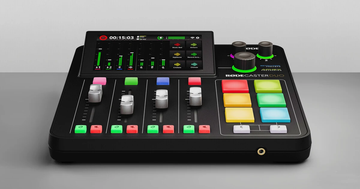 Rode RodeCaster Duo audio interface shows its touchscreen, four faders and colored sound pads on a gray surface