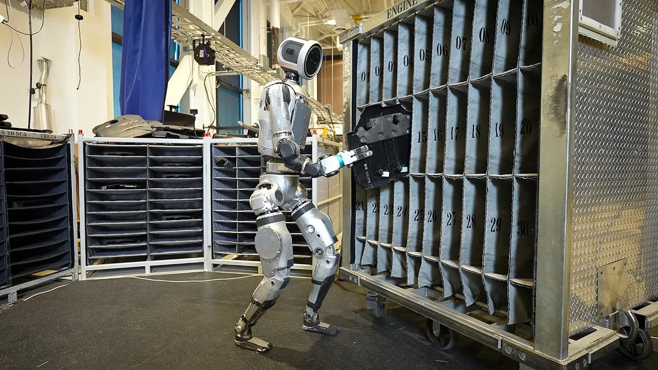 Atlas humanoid robot shows an industrial robot task, placing a part into a numbered storage rack