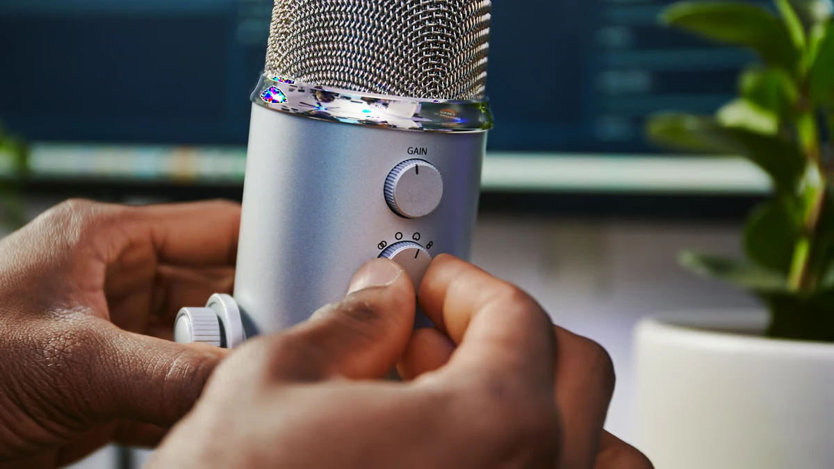 A person adjusts a Blue Yeti USB microphone for streaming.