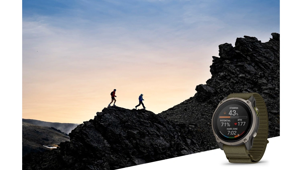 Garmin Enduro 4 smartwatch in the foreground with hikers on a rocky ridge behind it