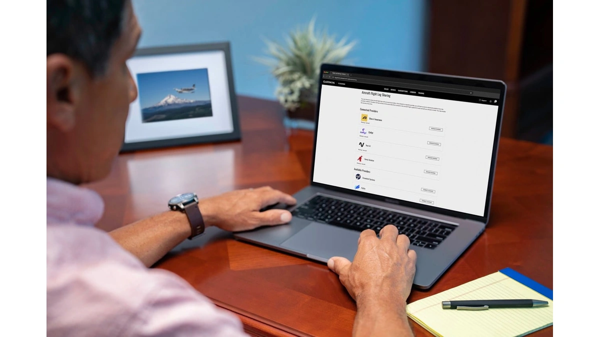 Pilot at a laptop viewing flyGarmin.com flight log sharing, with Class A and Coflyt listed as connected providers
