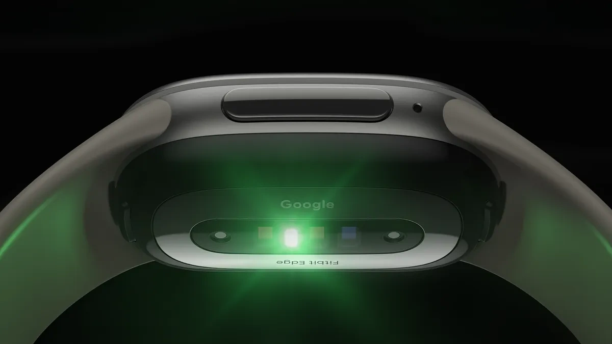 Fitbit Edge seen from below, its sensor array glowing green against a black background