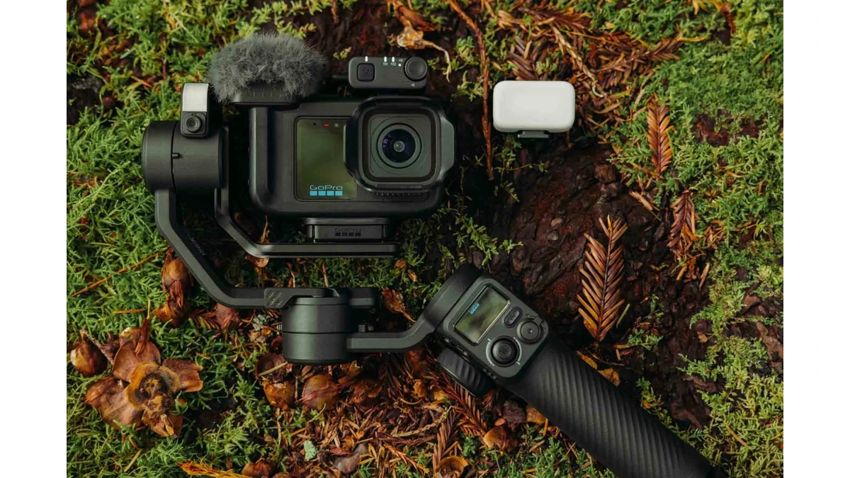 GoPro camera on a gimbal grip with a windscreen microphone, light panel, and wireless transmitter on forest moss