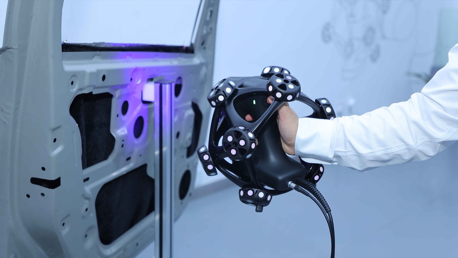 HYPERSCAN SR handheld 3D scanner held up to a car door panel during an inspection