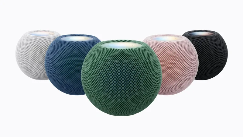Five HomePod mini speakers in white, blue, green, pink and black mesh arranged on a white background