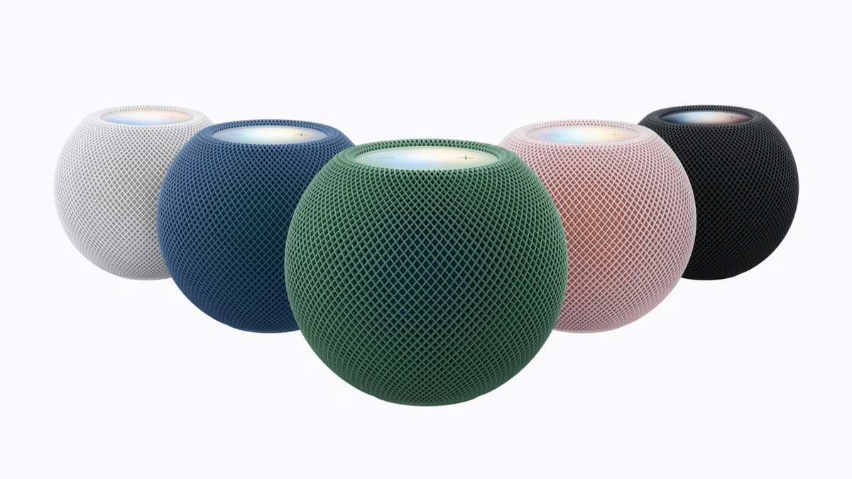 Five HomePod mini speakers in white, blue, green, pink and black mesh arranged on a white background