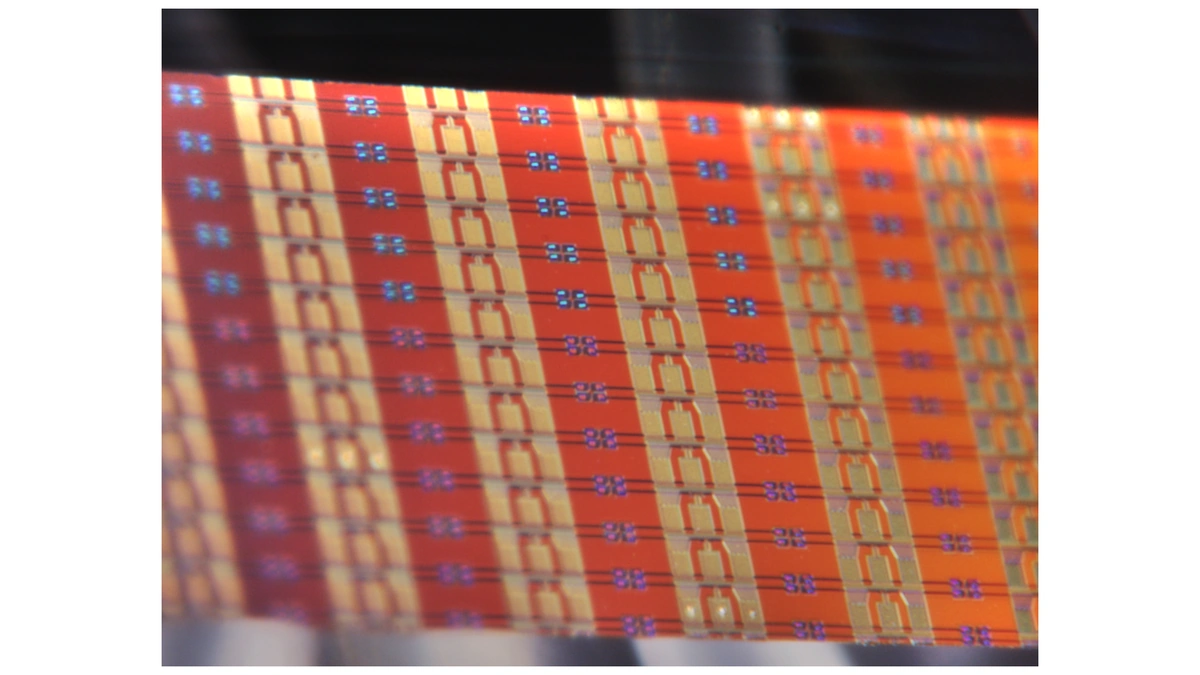 imec silicon photonics wafer close-up: repeating orange and gold device patterns with small blue and purple squares