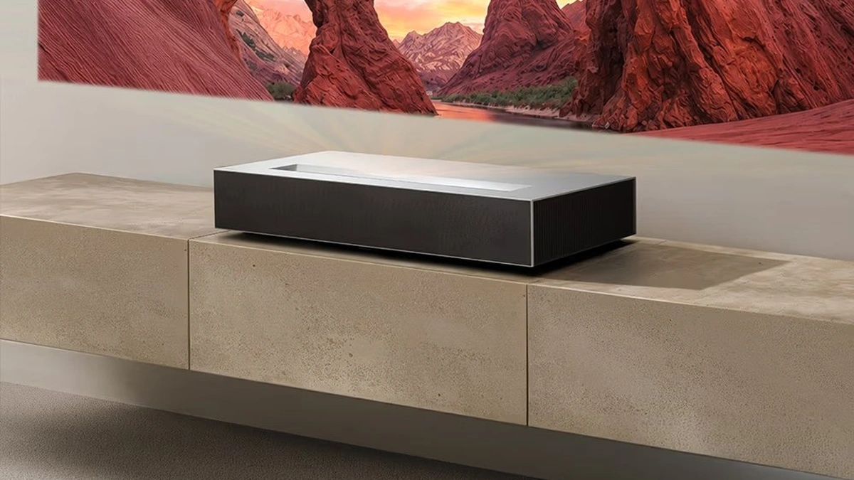 LG CineBeam AI HU925V ultra-short-throw projector on a media console projecting a red canyon sunset image on the wall