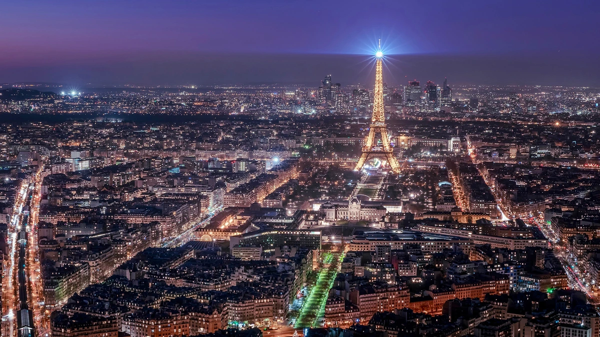 Aerial view of Paris at night with the illuminated Eiffel Tower and city skyline