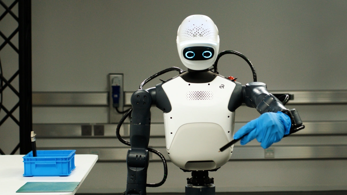 NVIDIA Isaac platform humanoid robot with a white head and torso and a blue gloved hand in front of a gray wall