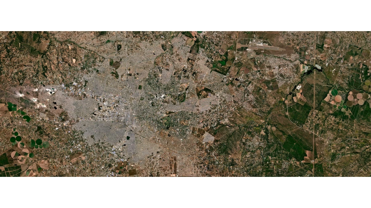 Planet Populace satellite view of a dense city spreading into surrounding farmland