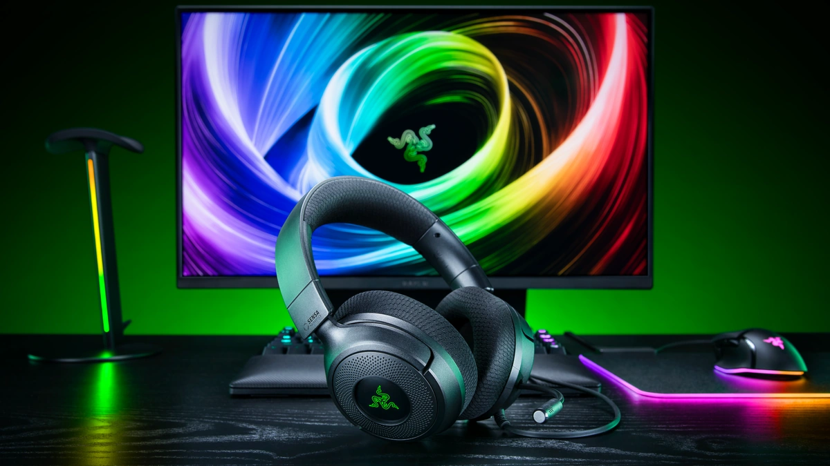Razer Kraken V4 X headset on a desk in front of a monitor with swirling RGB wallpaper