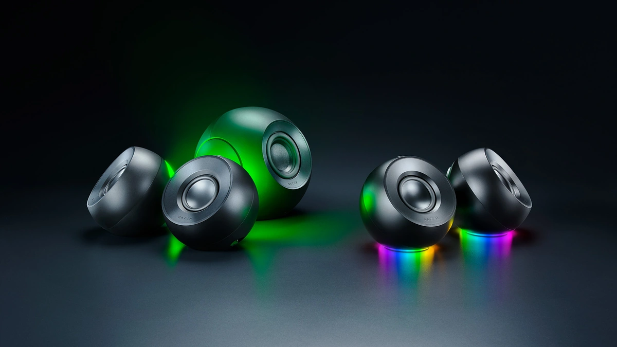 Razer Mako desktop gaming speakers, round black units lit with green and rainbow Chroma RGB on a dark surface
