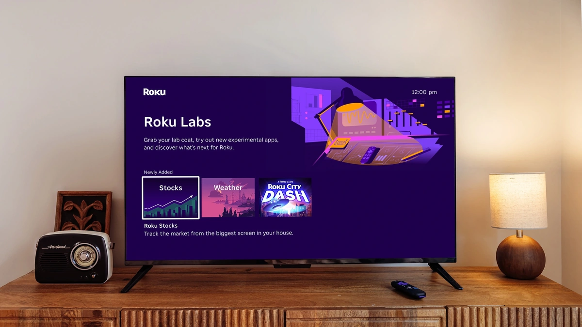 Roku Labs screen on a living-room TV showing Stocks, Weather, and Roku City Dash tile options