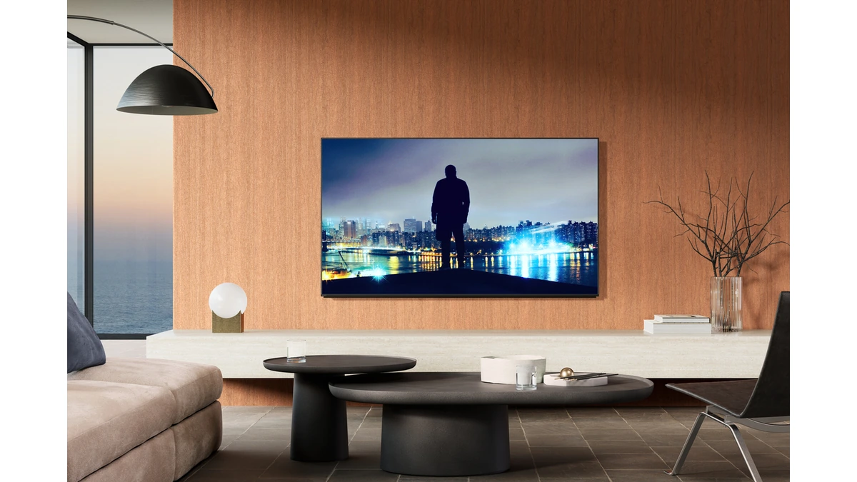 Sony BRAVIA 8 II OLED TV wall-mounted, showing a figure standing before a night city skyline