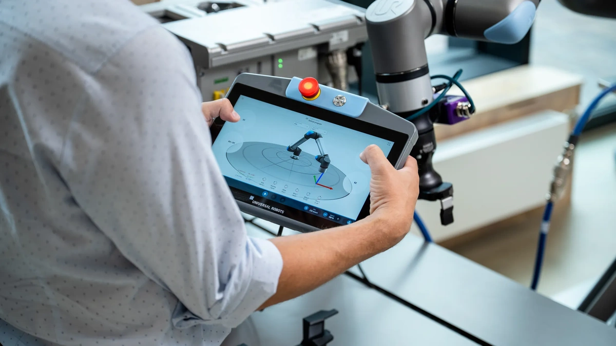 Universal Robots teach pendant showing a 3D cobot arm model beside a collaborative robot arm